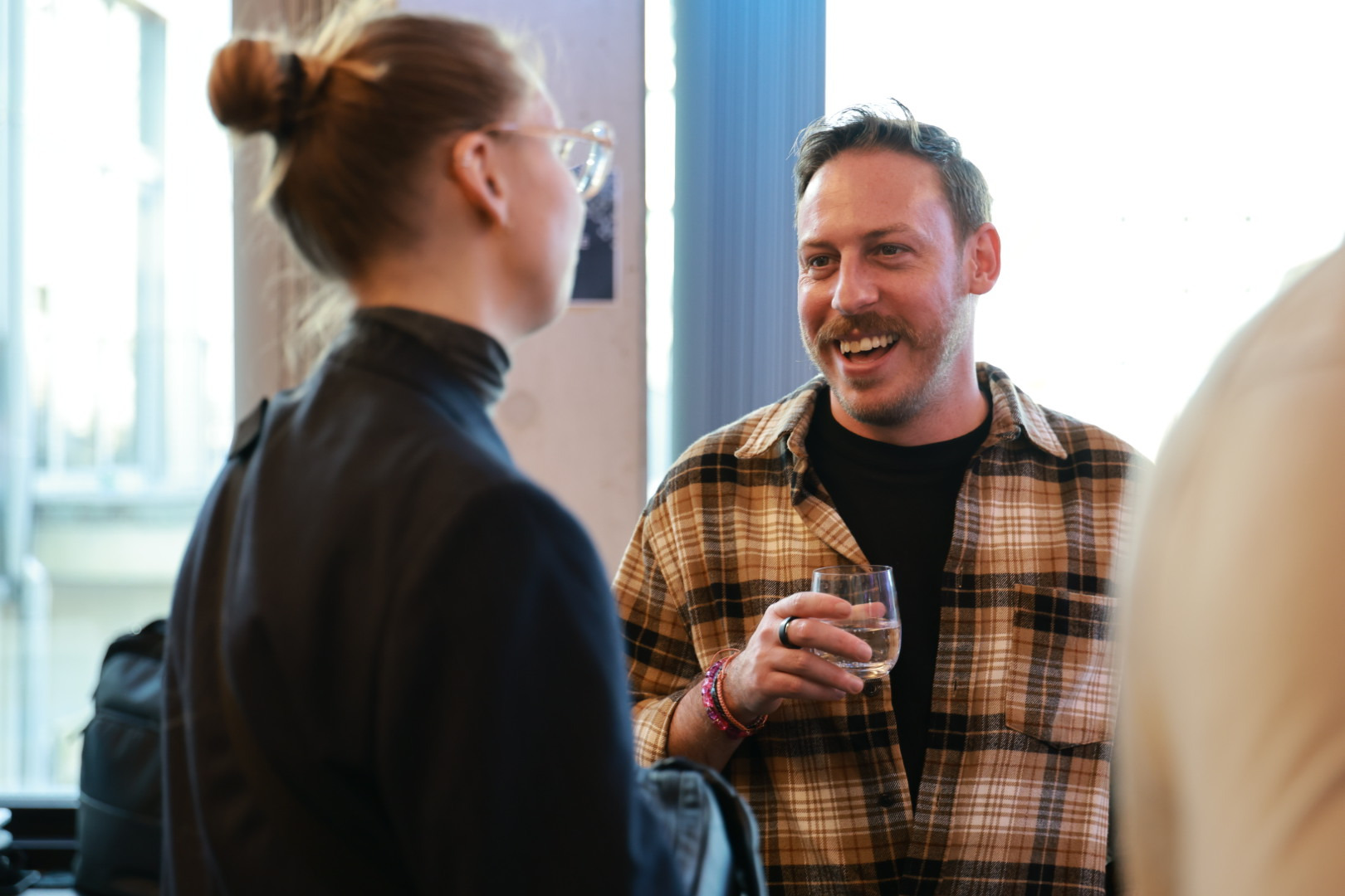 Tim Cakir laughing in conversation with a participant during a break at a client kick-off in Munich.